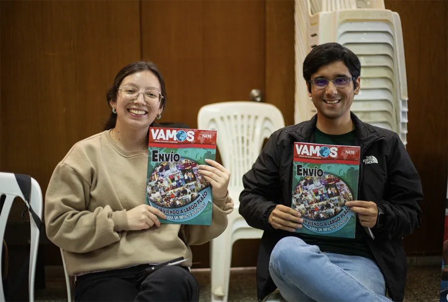 Dos jóvenes sonríen sosteniendo un ejemplar de la revista VAMOS